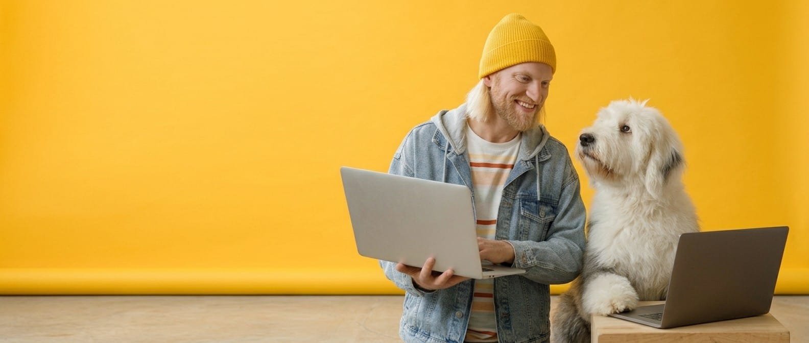 Een vrolijke man met een laptop naast een grote witte herdershond